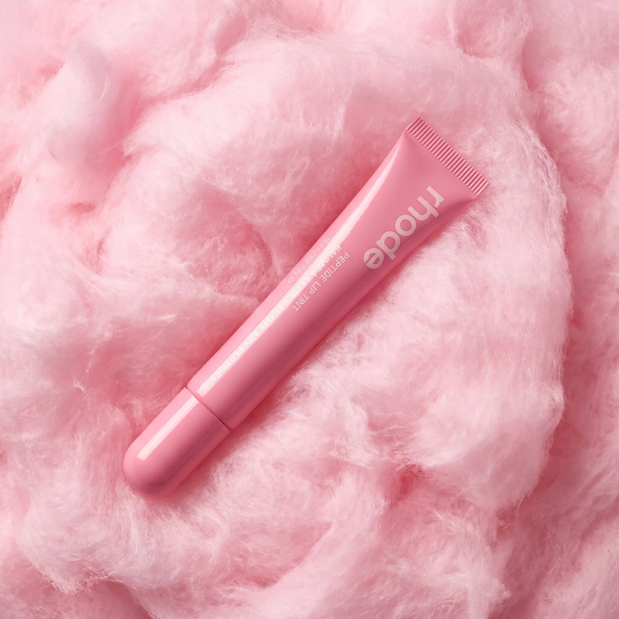 Rhode peptide lip tint tube resting on a bed of pink cotton candy